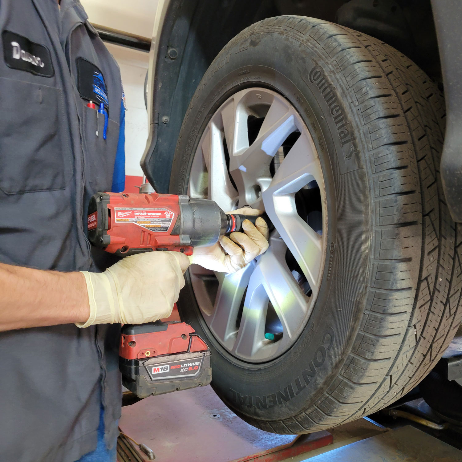 A mechanic removing lug nuts from wheel before maintenance services